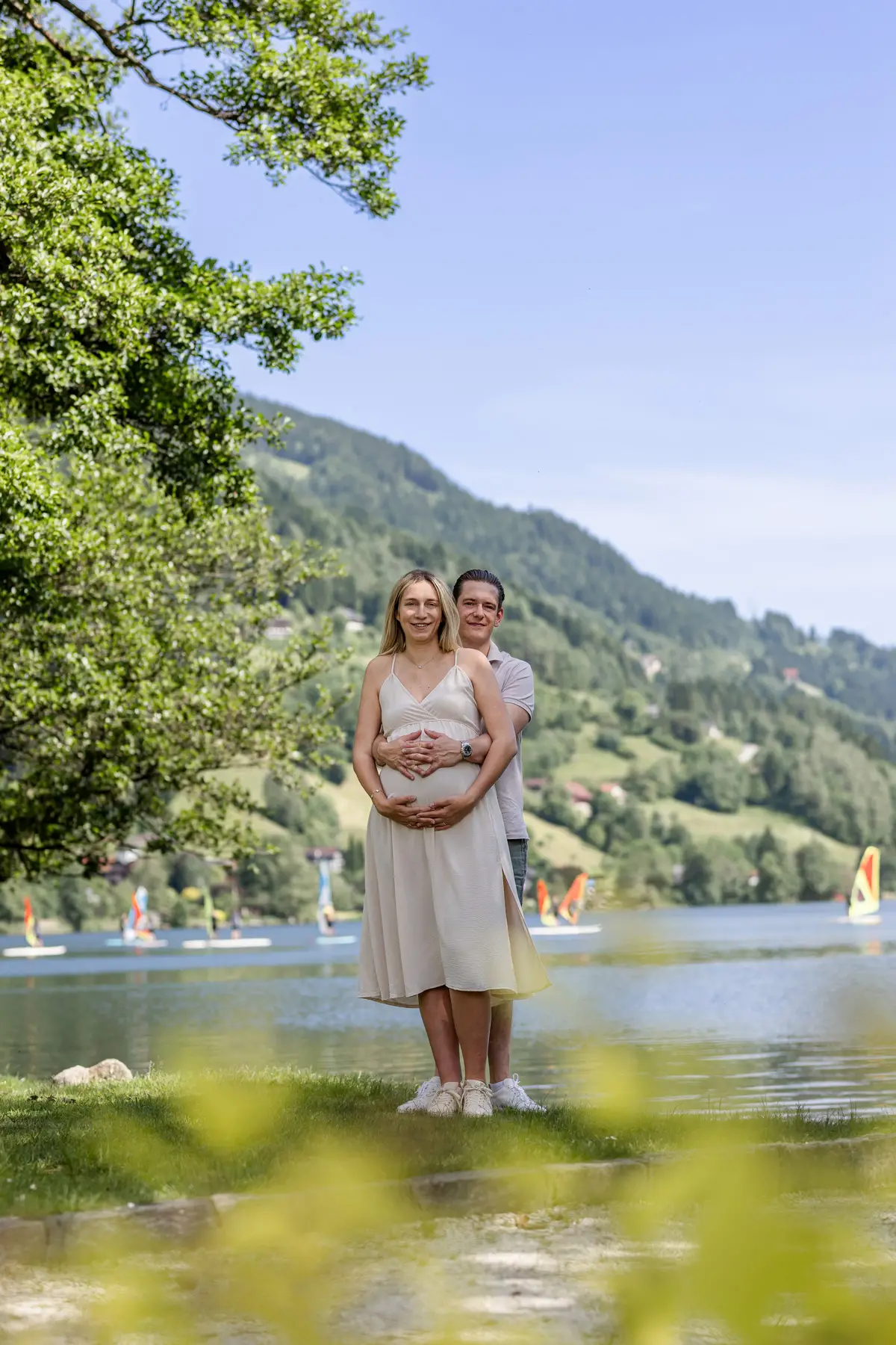 Bild-von-werdenden-Eltern-mit-Babybauch-vor-einem-Bergsee